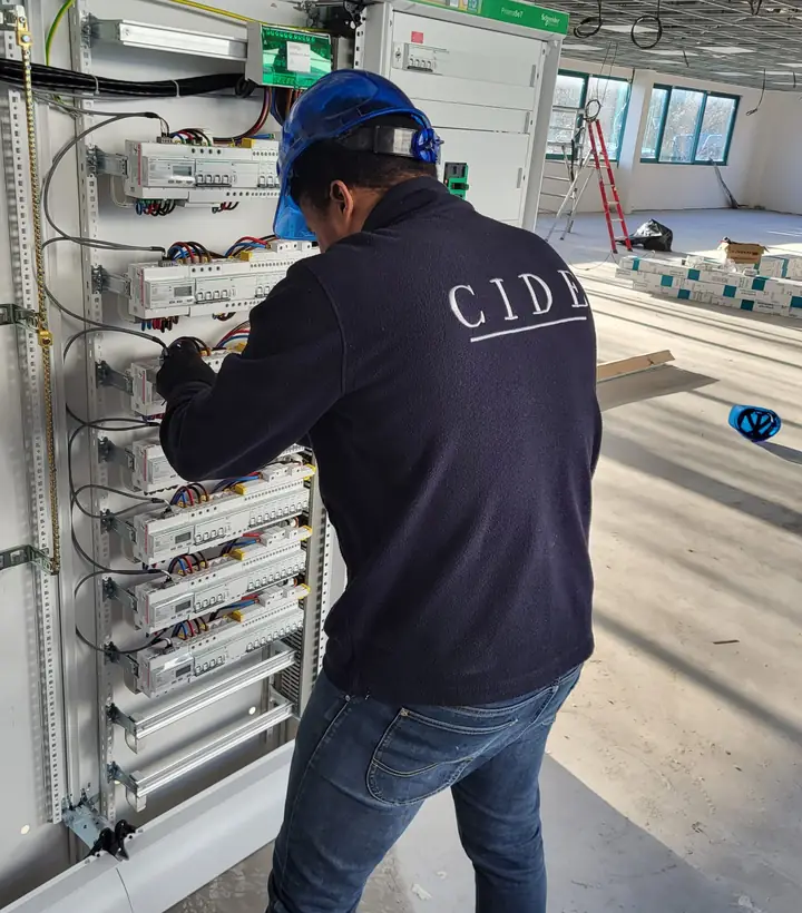 Électricien CIDE intervenant sur une armoire de distribution en bâtiment tertiaire