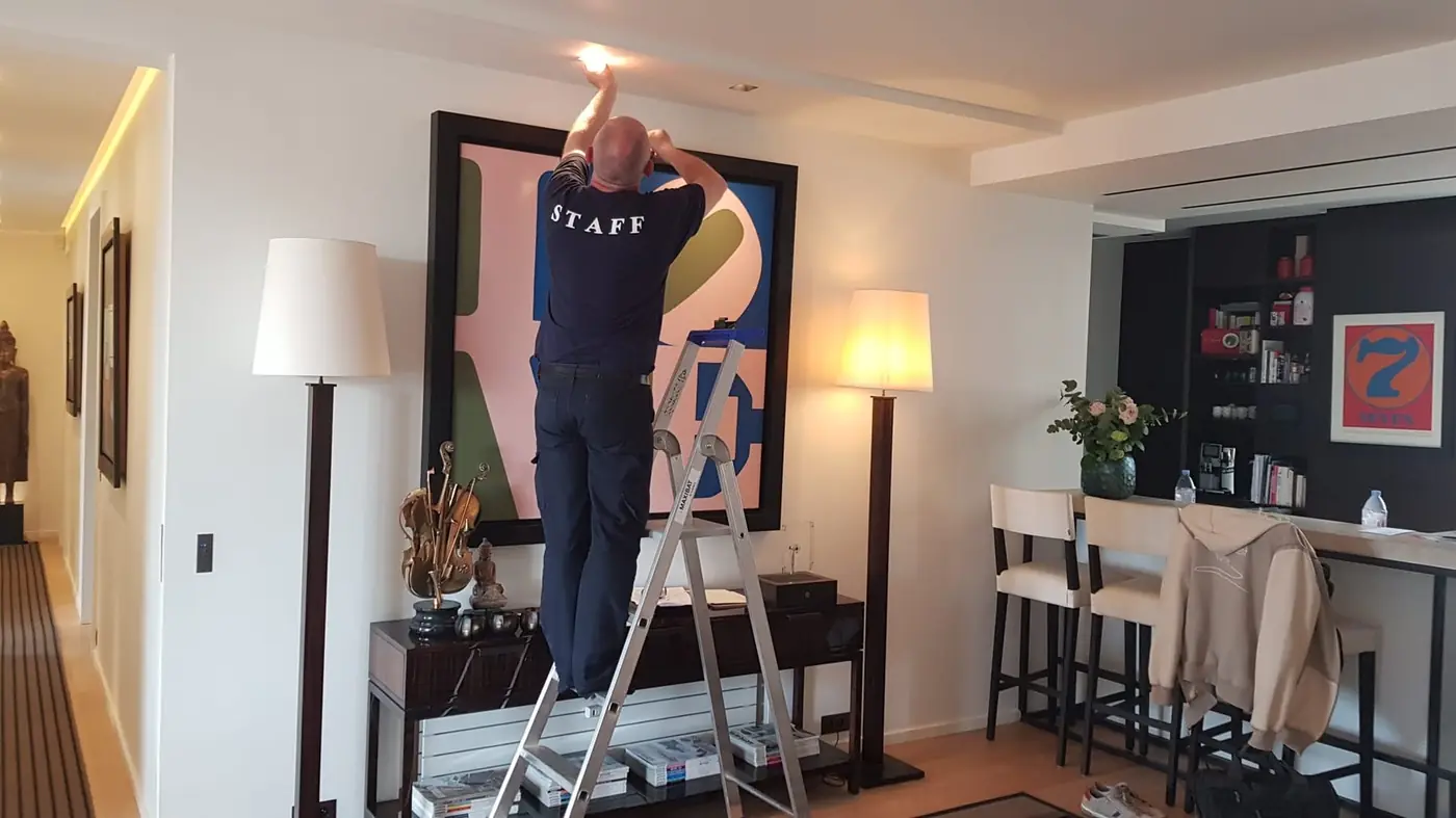 Technicien CIDE installant un spot encastré au plafond d'un salon en Île-de-France